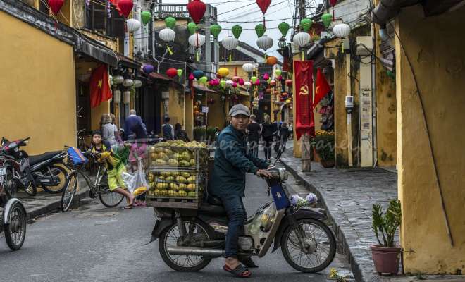 Mango fruit seller on old Hoi An street, festooned with lanterns